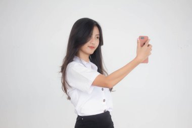Taylandlı yetişkin öğrenci üniformasının portresi. Güzel kız akıllı telefonuyla selfie çekiyor.