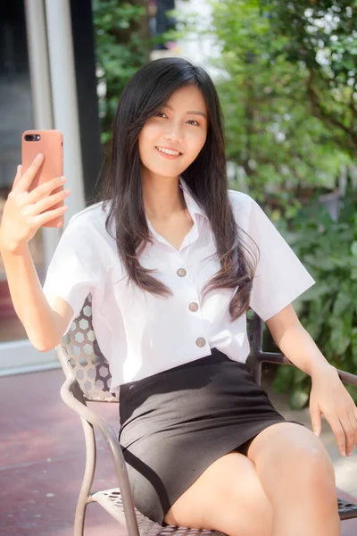 Portrait of thai adult student university uniform beautiful girl using her smart phone