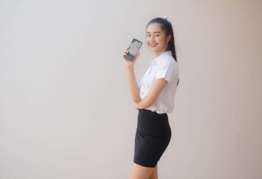 Taylandlı yetişkin öğrenci üniforması portresi. Güzel kız akıllı telefonunu göster.