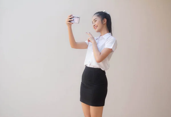 タイのポートレート大人学生大学制服美しいです女の子使用して彼女のスマートフォンSelfie — ストック写真