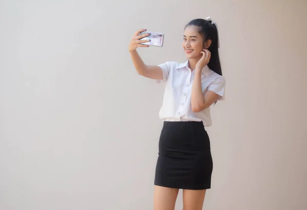 タイのポートレート大人学生大学制服美しいです女の子使用して彼女のスマートフォンSelfie — ストック写真