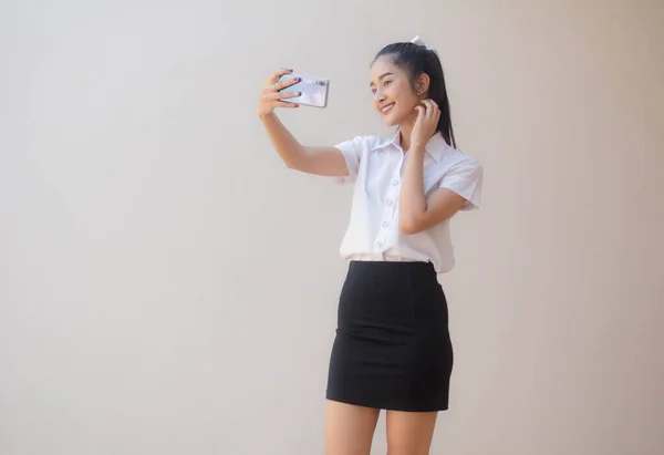 タイのポートレート大人学生大学制服美しいです女の子使用して彼女のスマートフォンSelfie — ストック写真