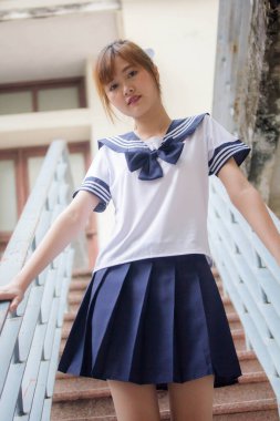Taylandlı genç kız portresi Japon öğrenci üniforması içinde mutlu ve rahatlamış.
