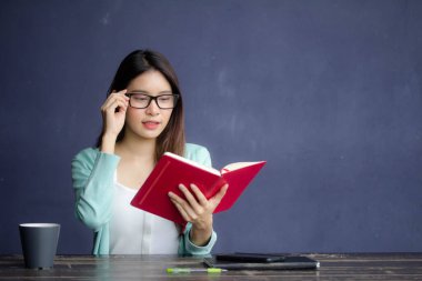 Tayland porseleni yetişkin ofis kızı gözlükleri kırmızı kitap okuyan beyaz gömlek