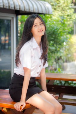 Taylandlı yetişkin öğrenci üniforması portresi. Güzel kız rahatla ve gülümse.