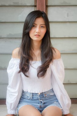 Taylandlı yetişkin güzel kız portresi. Beyaz gömlek, mavi kot pantolon, rahatla ve gülümse.