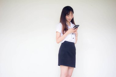 Taylandlı yetişkin öğrenci üniformasının portresi. Akıllı telefonunu kullanan güzel bir kız.