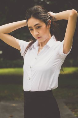 Taylandlı yetişkin öğrenci üniforması portresi. Güzel kız rahatla ve gülümse.