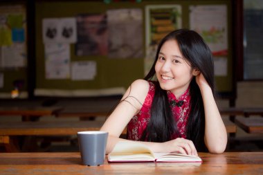 Taylandlı ergen portresi. Çinli elbiseli güzel kız. Bir kitap okumuş..