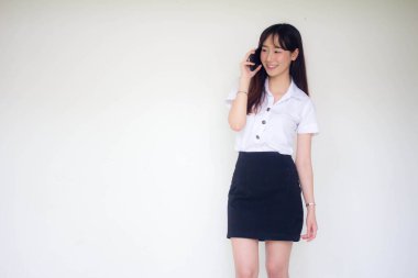 Taylandlı yetişkin öğrenci üniformasının portresi. Güzel bir kız akıllı telefondan arıyor.