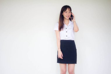 Taylandlı yetişkin öğrenci üniformasının portresi. Güzel bir kız akıllı telefondan arıyor.