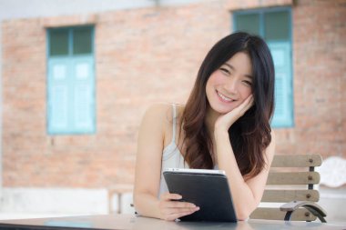 Tayland portresi. Yetişkin güzel bir kız. Tabletini kullanan beyaz gömlek..