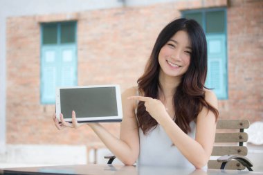 Tayland portresi. Yetişkin güzel bir kız. Tabletini kullanan beyaz gömlek..