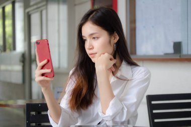 Taylandlı yetişkin kadınların portresi. Akıllı telefon kullanan beyaz gömlek.