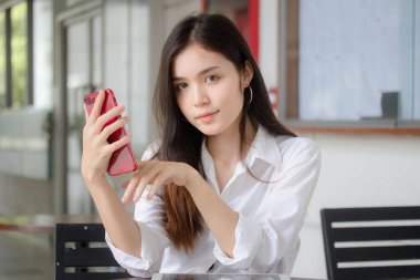 Taylandlı yetişkin kadınların portresi. Akıllı telefon kullanan beyaz gömlek.