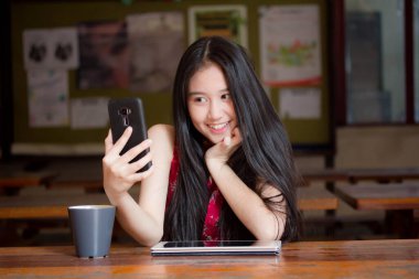 Taylandlı genç kız portresi. Çinli elbiseli güzel kız. Akıllı telefon özçekimi kullanıyor.