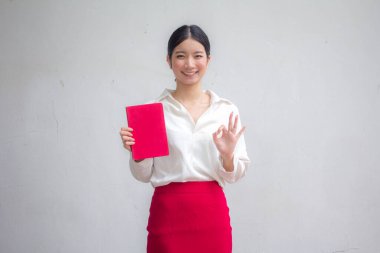 Taylandlı yetişkin kadınların portresi. Kırmızı kitap okuyan beyaz gömlek.