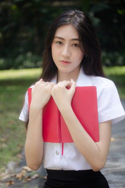 Taylandlı yetişkin öğrenci üniforması portresi. Güzel kız kırmızı kitabı okudu.