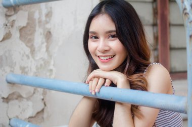 Taylandlı yetişkin güzel bir kızın portresi. Beyaz gömlek, mavi kot pantolon rahatlama zamanı.