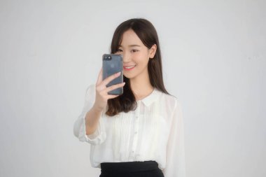 Taylandlı yetişkin kadınların portresi beyaz gömlekli akıllı telefon özçekimini kullanıyor.