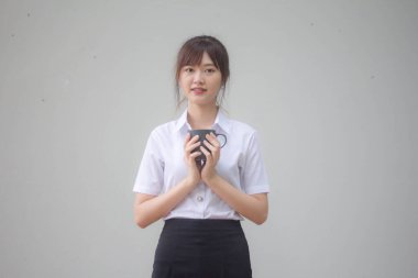 Taylandlı yetişkin öğrenci üniformasının portresi. Güzel kahve içiyor.