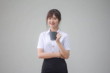 Taylandlı yetişkin öğrenci üniformasının portresi. Güzel kahve içiyor.