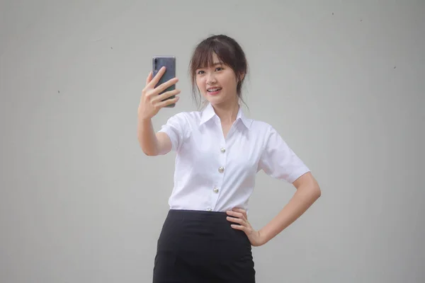 タイのポートレート大人学生大学制服美しいです女の子使用して彼女のスマートフォンSelfie — ストック写真