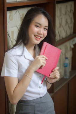 Taylandlı yetişkin öğrenci üniforması güzel kız rahatla ve gülümse.