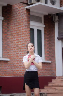 Taylandlı yetişkin öğrenci üniforması güzel kız rahatla ve gülümse.