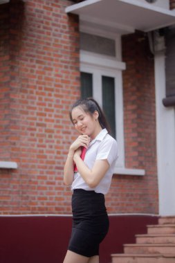 Taylandlı yetişkin öğrenci üniforması güzel kız rahatla ve gülümse.