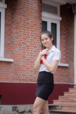 Taylandlı yetişkin öğrenci üniforması güzel kız rahatla ve gülümse.