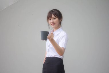 Taylandlı yetişkin öğrenci üniformasının portresi. Güzel kahve içiyor.