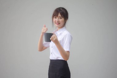 Taylandlı yetişkin öğrenci üniformasının portresi. Güzel kahve içiyor.