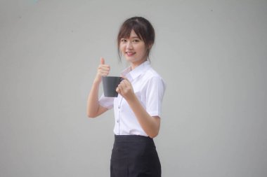 Taylandlı yetişkin öğrenci üniformasının portresi. Güzel kahve içiyor.