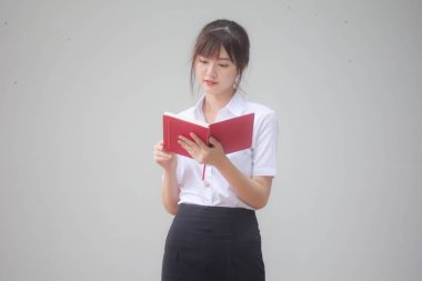 Taylandlı yetişkin öğrenci üniforması portresi. Güzel kız kırmızı kitabı okudu.