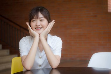 Taylandlı yetişkin öğrenci üniforması portresi. Güzel kız rahatla ve gülümse.