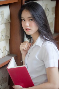 Taylandlı yetişkin üniversite üniforması güzel kız kırmızı kitabı okuyor.