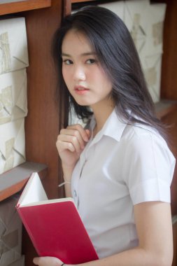 Taylandlı yetişkin üniversite üniforması güzel kız kırmızı kitabı okuyor.