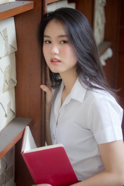 Taylandlı yetişkin üniversite üniforması güzel kız kırmızı kitabı okuyor.