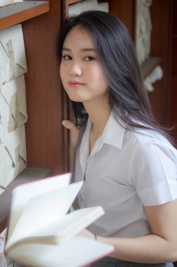 Taylandlı yetişkin üniversite üniforması güzel kız kırmızı kitabı okuyor.