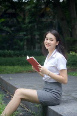 Taylandlı yetişkin üniversite üniforması güzel kız kırmızı kitabı okuyor.