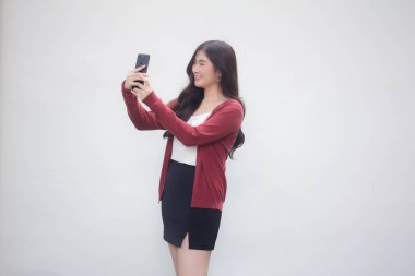 Taylandlı yetişkin kadın portresi XI beyaz gömlek, akıllı telefon özçekimini kullanıyor.