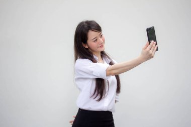 Çin portresi yetişkin ofis kızı beyaz gömlek akıllı telefonuyla selfie çekiyor.