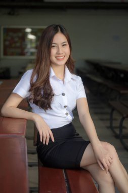 Taylandlı yetişkin öğrenci üniforması güzel kız rahatla ve gülümse.