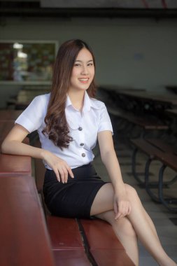 Taylandlı yetişkin öğrenci üniforması güzel kız rahatla ve gülümse.