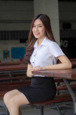 Taylandlı yetişkin öğrenci üniforması güzel kız rahatla ve gülümse.