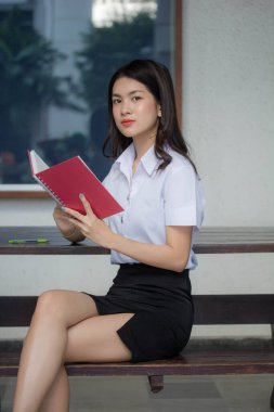 Taylandlı yetişkin üniversite üniforması güzel kız kırmızı kitabı okuyor.