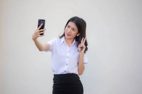 タイの成人女子大生制服美少女使用彼女のスマートフォンSelfie — ストック写真