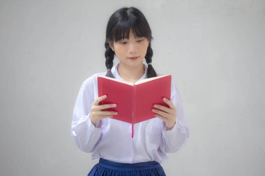 Asya Taylandlı lise öğrencisi üniforması. Güzel kız bir kitap okumuş.