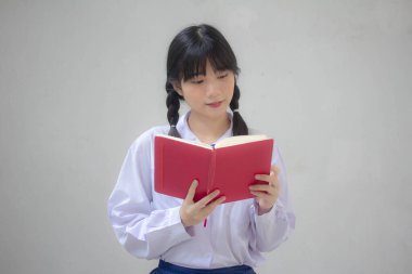 Asya Taylandlı lise öğrencisi üniforması. Güzel kız bir kitap okumuş.